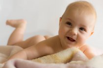 Portrait de bébé garçon souriant allongé sur une couverture — Photo de stock