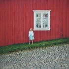 Fille debout contre la maison rouge — Photo de stock
