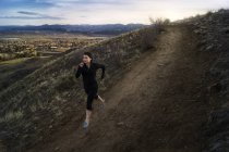 Estados Unidos, Colorado, Condado de Jeferson, Golden, Mujer corriendo por la carretera de la ladera - foto de stock