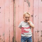 Petit garçon souriant debout devant la porte de garage rose — Photo de stock