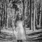 Retrato de niña triste vestida de blanco vestido festivo de pie en el bosque - foto de stock