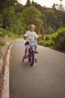 Girl riding bicycle on country road — Stock Photo