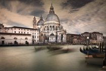 Italy, Venice, Cathedral seen across canal, with blurred silhouettes of gondolas in foreground — Stock Photo