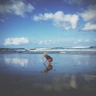 Хлопчик грає на пляжі з хмарним небом на фоні — стокове фото