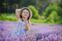 Kleines Mädchen, das Blumen im Lavendelfeld riecht — Stockfoto