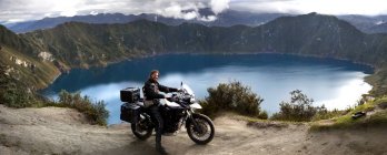 Еквадор, людина на мотоциклі стоячи проти озеро в Лагуна Кілотоа — стокове фото