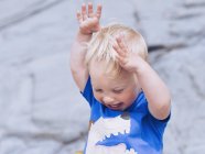 Крупним планом портрет чарівного маленького хлопчика, який сміється з піднятими руками — стокове фото