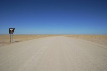 Vista panorámica a lo largo del camino vacío del desierto con señal de área de descanso, Namibia - foto de stock