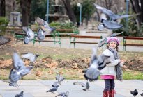 Little girl feeding pigeons outdoors — Stock Photo