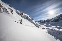 Austria, esquiador masculino subiendo en las montañas - foto de stock