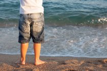 Primo piano di gambe maschili in piedi sulla spiaggia — Foto stock