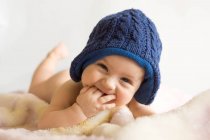 Retrato de menino vestindo chapéu azul de malha deitado no cobertor — Fotografia de Stock