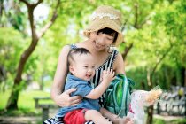 Felice famiglia asiatica, mamma seduta nel parco con il bambino — Foto stock