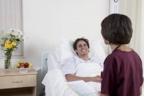 Felice giovane uomo in ambulatorio medico ufficio con medico femminile — Foto stock