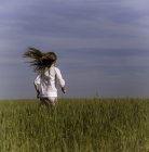 Маленькая девочка бежит по зеленому полю — стоковое фото