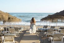 Visão traseira da jovem loira caminhando em direção à praia — Fotografia de Stock