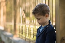 Портрет грустного мальчика, опирающегося на забор — стоковое фото