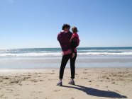 Mãe segurando filha na praia — Fotografia de Stock