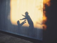 Sombras de duas crianças brincando contra a parede — Fotografia de Stock