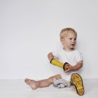 Маленький хлопчик одягає черевики у Веллінгтон на білому тлі — стокове фото