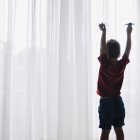 Мальчик играет с игрушками самолетов рядом с окном — стоковое фото
