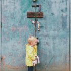 Junge steht vor verschlossener schäbiger Tür — Stockfoto