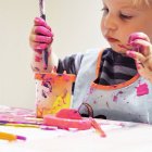 Мальчик делает беспорядок во время рисования за столом — стоковое фото