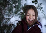 Chica con los ojos cerrados de pie en las ramas de los árboles nevados - foto de stock
