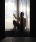 Homem sentado no peitoril da janela com o braço estendido e olhando para a vista — Fotografia de Stock