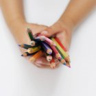 Обрізане зображення дитячих рук, що тримають кольорові олівці — стокове фото