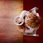 Visão aérea da menina comendo mirtilos na mesa de madeira — Fotografia de Stock