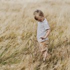 Curieux petit garçon debout dans la prairie — Photo de stock
