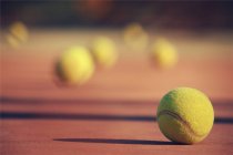 Vista de cerca de las pelotas de tenis en la cancha, fondo borroso - foto de stock