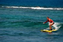 Femme attrapant vague sur planche de surf dans l'océan — Photo de stock