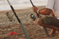 Imagen recortada de Hombre pescando en la playa de arena - foto de stock
