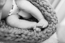 Cropped image of bare legs of newborn wearing diaper, monochrome — Stock Photo