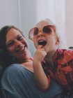 Portrait of happy mother and daughter in sunglasses at home — Stock Photo