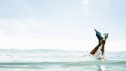 Обрезанное изображение мужских ног с ластами торчащими из моря — стоковое фото