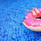 Обрезанный образ человека, расслабляющегося на надувном пончике в бассейне — стоковое фото