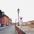 Italia, Toscana, Pisa, Chica con paraguas caminando por la cornisa - foto de stock