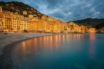 Italia, Liguria, Génova, Camogli, Primera línea de mar con luces eléctricas que reflejan en el agua - foto de stock