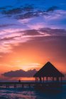 Bellissimo cielo rosa viola tramonto, molo con casa e acqua di mare — Foto stock