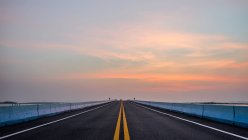 Estrada através da rodovia com belo fundo pôr do sol — Fotografia de Stock
