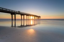 Beautiful sunset sky and pier on sea water — Stock Photo