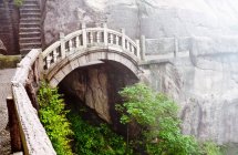 Puente de piedra brumoso en las montañas de Huangshan, China - foto de stock