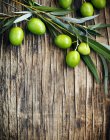 Olive verdi fresche con foglie su fondo di legno — Foto stock