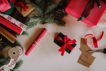 Різдвяний фон з подарунками, ялинковими гілками, червоною стрічкою, подарунковими коробками, вид зверху — стокове фото