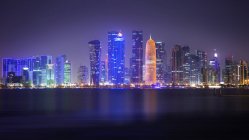Vista del horizonte de Doha a lo largo de la bahía de Doha en la noche en Qatar - foto de stock