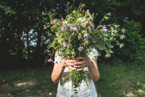 Frau hält Blumenstrauß im Wald. — Stockfoto