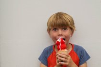 Ragazzo mangiare un gelato su sfondo bianco parete — Foto stock